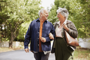 Senior couple smiling and walking down an outdoor path together representing peaceful Bloomingdale senior living in IL
