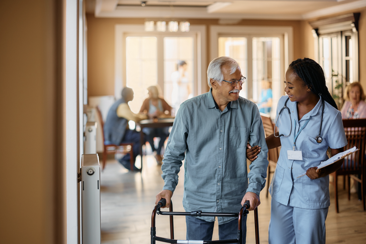 Senior man being escorted by caring staff member in senior living